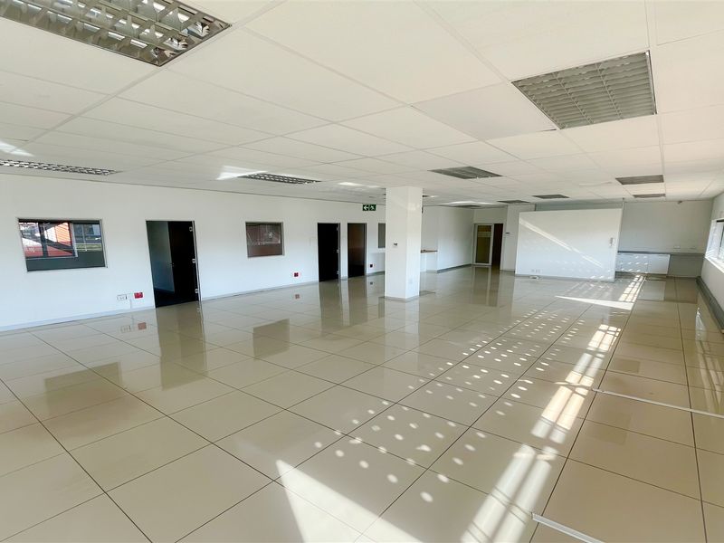 Spacious, open-plan office area featuring polished ceramic floor tiles, a suspended ceiling with recessed lighting, and a clean, neutral aesthetic.
