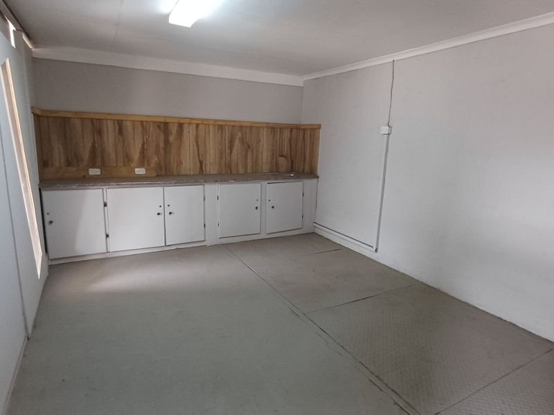 A functional utility space featuring built-in cabinetry, a countertop, and durable flooring, suitable for storage or workshop use.
