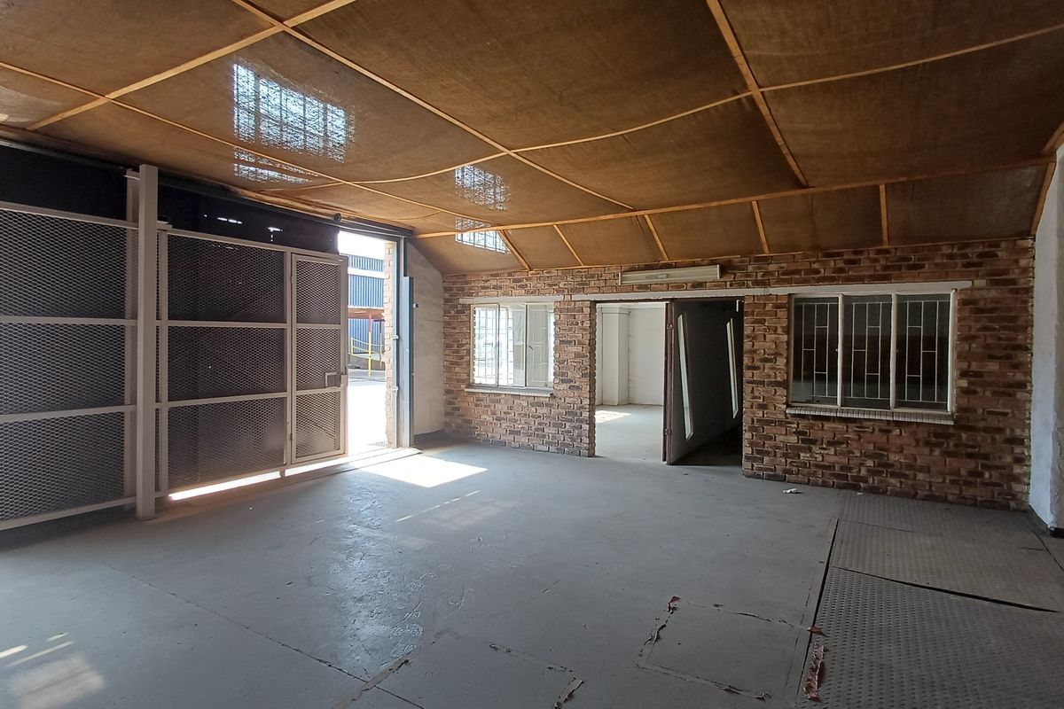 Spacious industrial utility area featuring exposed brick walls, concrete flooring, and a suspended mesh ceiling, suitable for workshop or storage use.