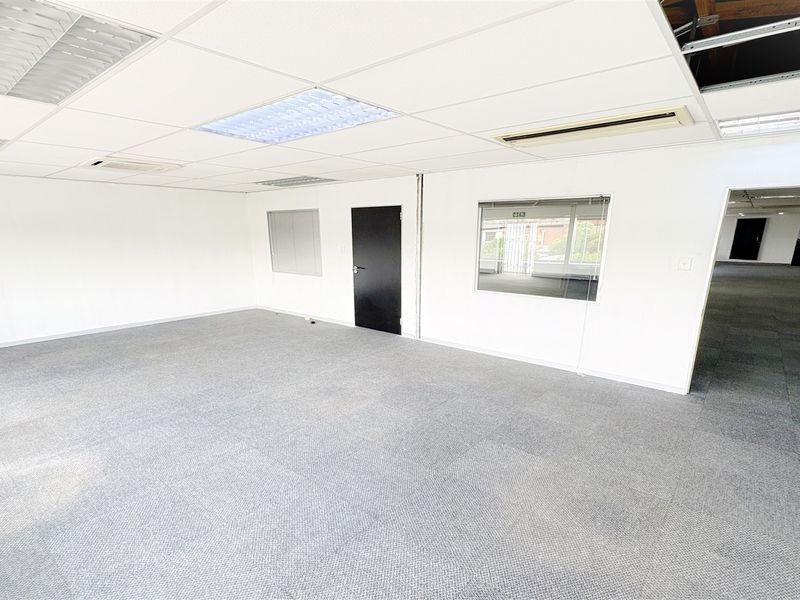 An open-plan office space featuring carpet tiles, a suspended ceiling with recessed lighting, and ducted air conditioning, currently vacant and ready for occupancy.