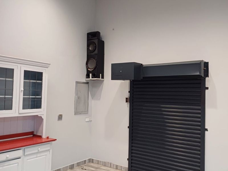 A clean utility or commercial space featuring tiled flooring, a suspended ceiling, and a secure roller shutter door.