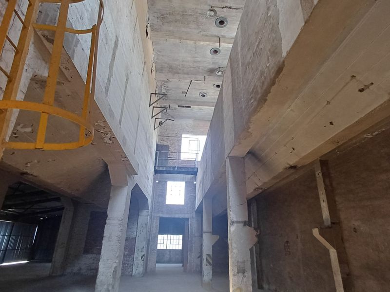 Expansive industrial utility space featuring high concrete ceilings, structural columns, and an integrated metal ladder, offering significant potential for redevelopment or adaptive reuse.