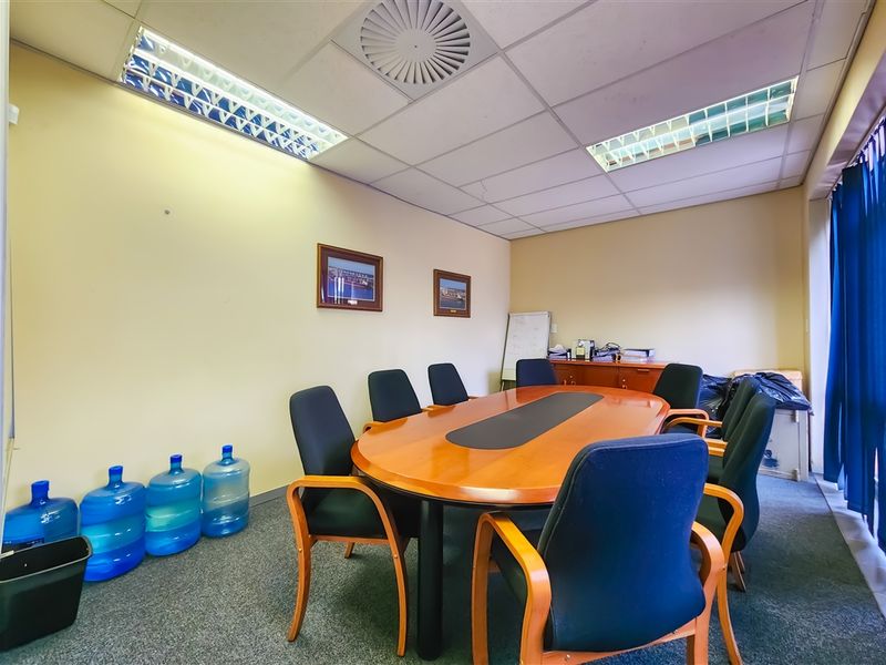 A functional office meeting room featuring a suspended ceiling with recessed lighting and carpeted flooring, suitable for professional use.