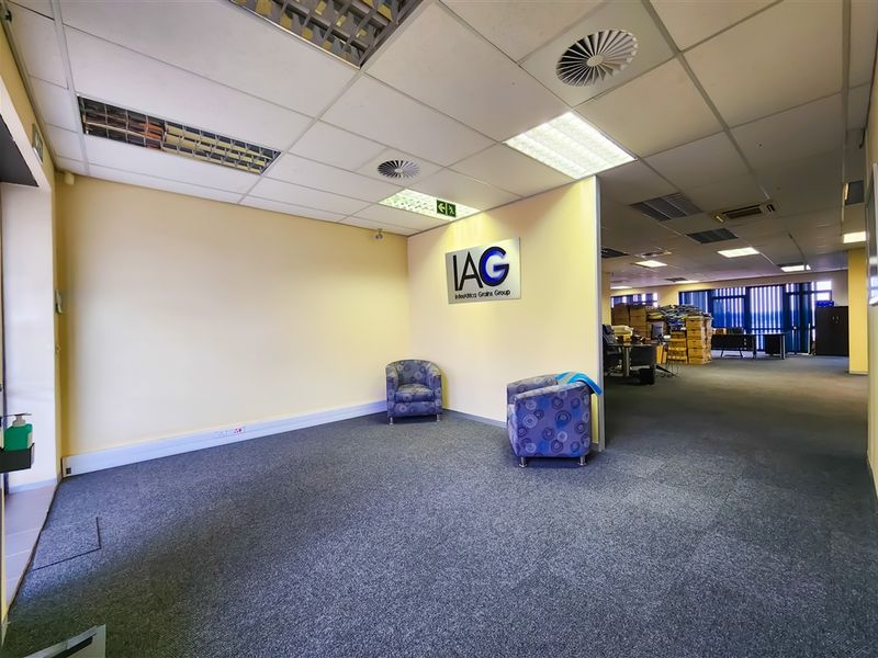 Open-plan office space featuring a suspended ceiling with recessed lighting, air conditioning vents, and carpeted flooring, suitable for a professional corporate environment.