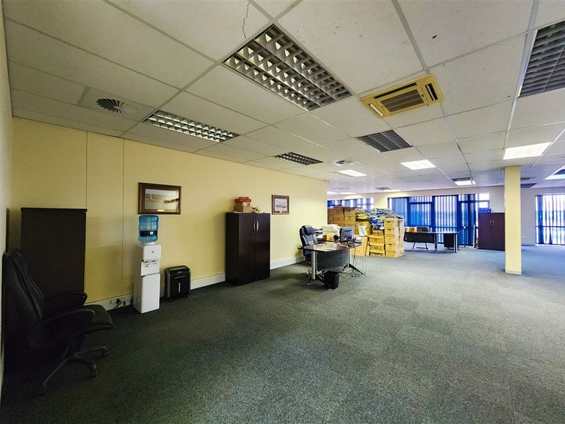Spacious open-plan office area featuring suspended ceilings, recessed lighting, ducted air conditioning, and large windows with vertical blinds.