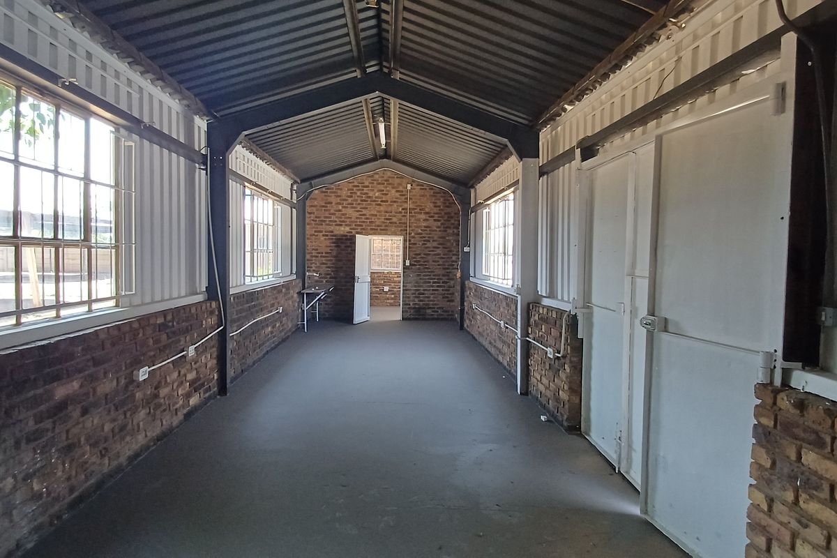 Spacious industrial-style office area featuring exposed brick walls, steel structural framing, concrete flooring, and large windows providing ample natural light.