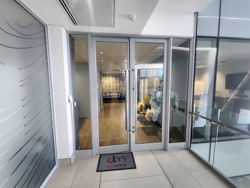 Modern office entrance featuring glass double doors, sleek tiled flooring, and professional glass partitioning, creating a bright and welcoming reception area.