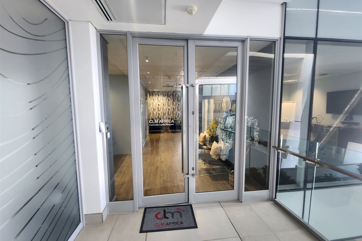 Modern office entrance featuring glass double doors, sleek tiled flooring, and professional glass partitioning, creating a bright and welcoming reception area.