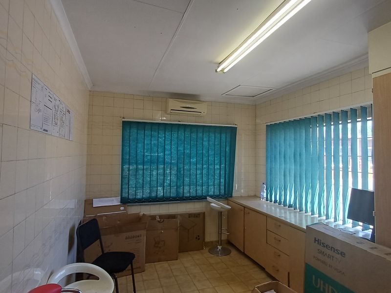Functional office space featuring built-in cabinetry, wall-mounted air conditioning, and vertical blinds, providing a practical workspace environment.