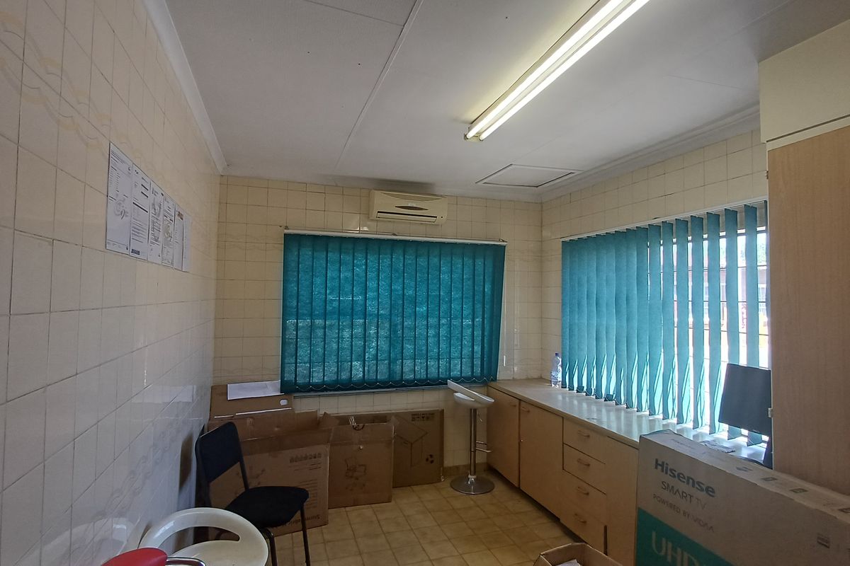 Functional office space featuring built-in cabinetry, wall-mounted air conditioning, and vertical blinds, providing a practical workspace environment.