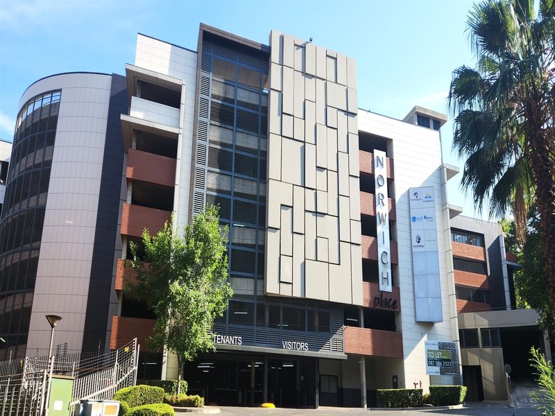 Front elevation of Norwich Place office building featuring a multi-level parking structure, modern facade cladding, and designated tenant and visitor entrance.