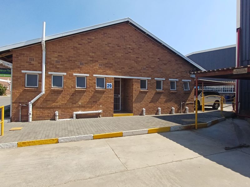 Front exterior view of a brick office building featuring a paved driveway, covered parking area, and secure entrance.