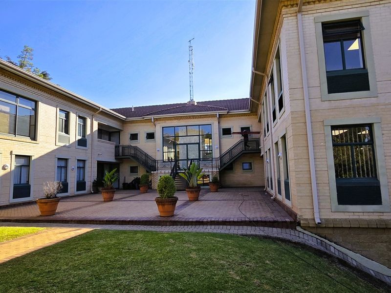 A well-maintained office building courtyard featuring paved surfaces, external staircases, and large windows, providing a professional and accessible outdoor space.