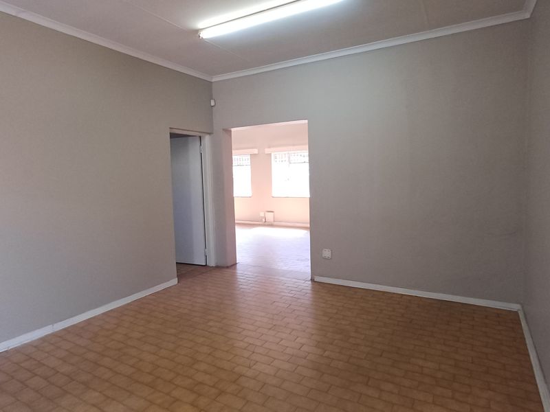 A vacant office space featuring neutral walls, vinyl tile flooring, and overhead fluorescent lighting, offering a clean and functional layout for professional use.