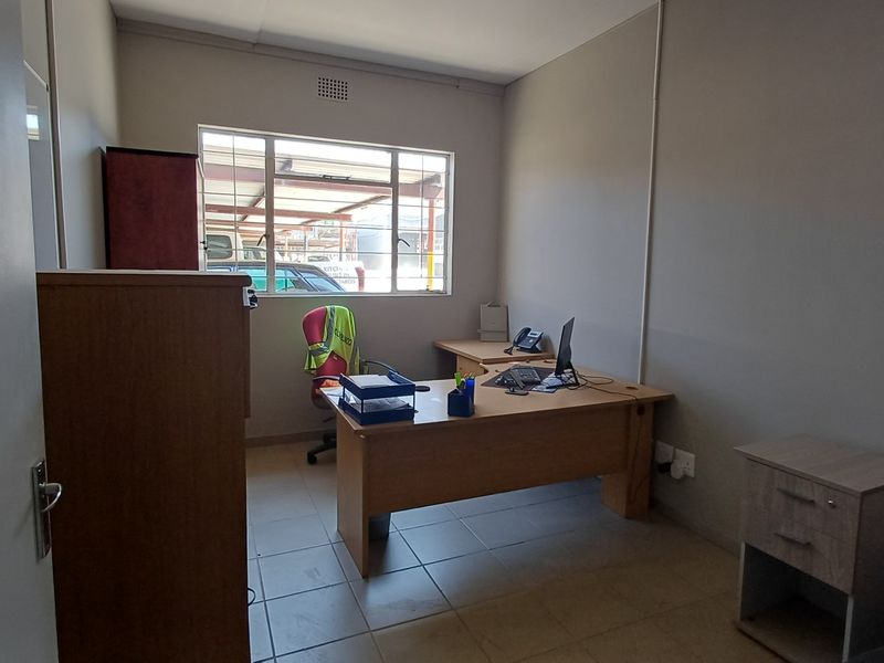 A functional office space featuring tiled flooring and a large window providing natural light, suitable for a professional work environment.
