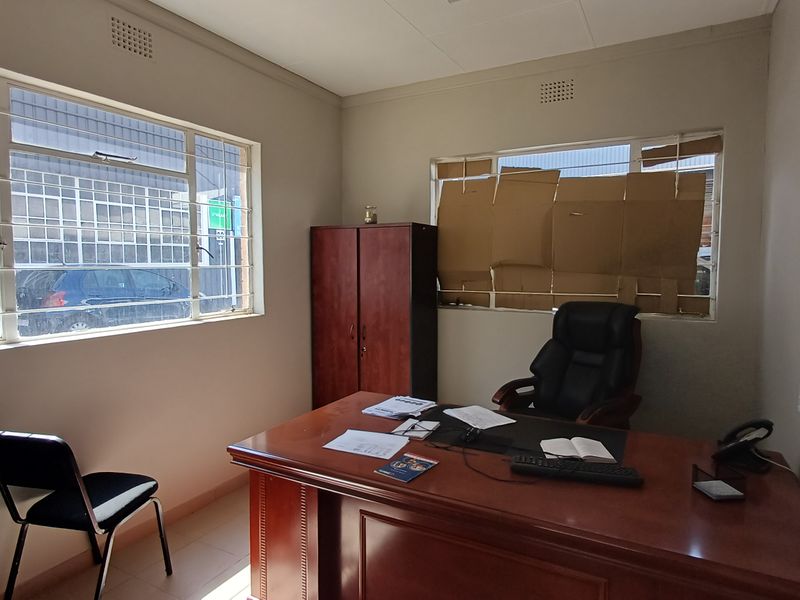 A functional office space featuring steel-framed windows and basic finishes, currently requiring minor repairs and cosmetic updates.