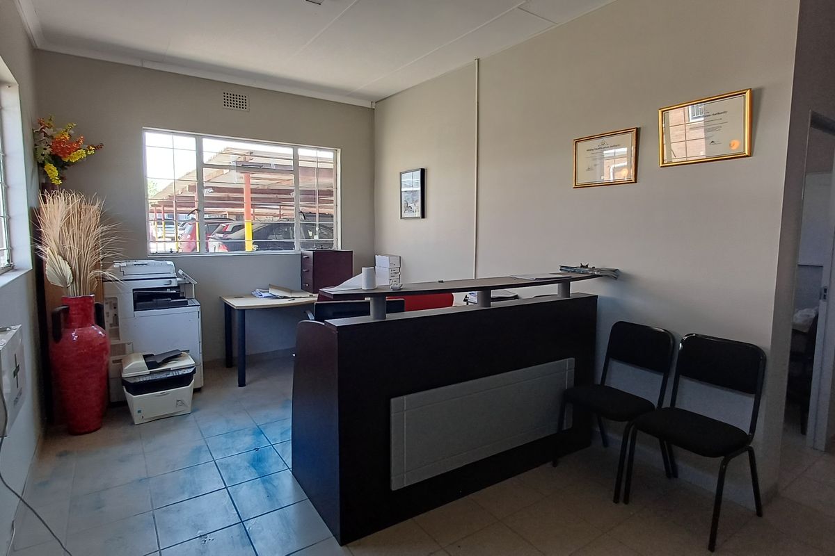 A functional office reception area featuring tiled flooring, aluminum windows, and a built-in reception desk, suitable for professional business operations.