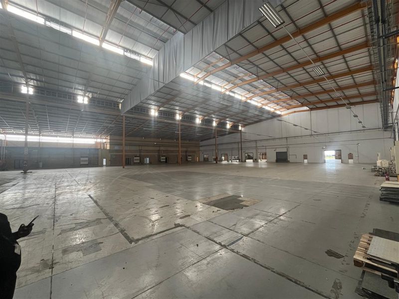 Large open-plan industrial warehouse space featuring high ceilings, steel portal frame construction, skylights, and multiple loading bay access points.