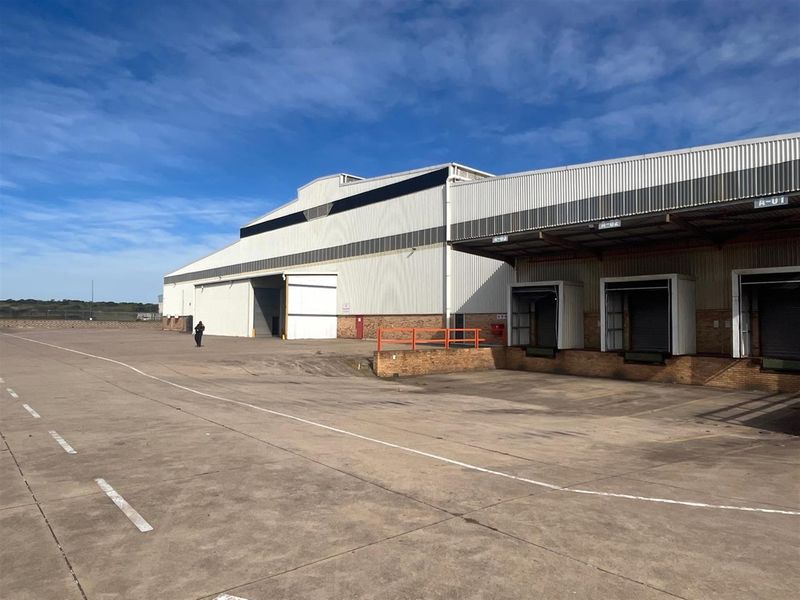 Industrial warehouse exterior featuring multiple loading docks with roller shutter doors and a large concrete yard area.