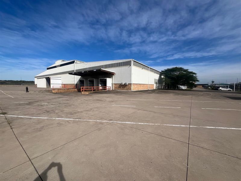 Industrial warehouse exterior featuring multiple loading docks, metal cladding, and a large concrete yard area suitable for logistics and heavy vehicle access.