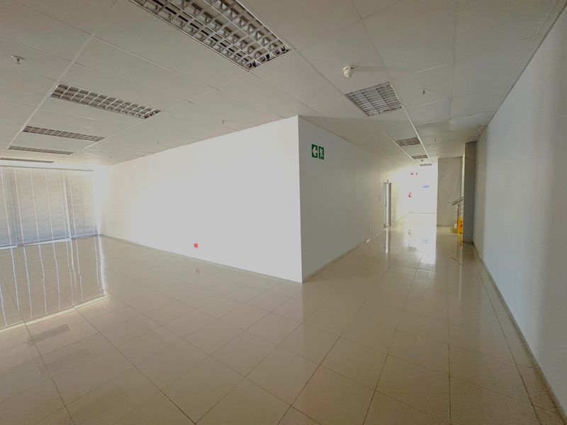 Spacious open-plan industrial office area featuring tiled flooring, suspended ceilings with recessed lighting, and large windows with fitted blinds.