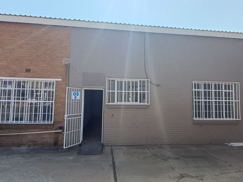 Front exterior view of an office unit featuring a brick facade, security bars on windows, and a metal security gate entrance.
