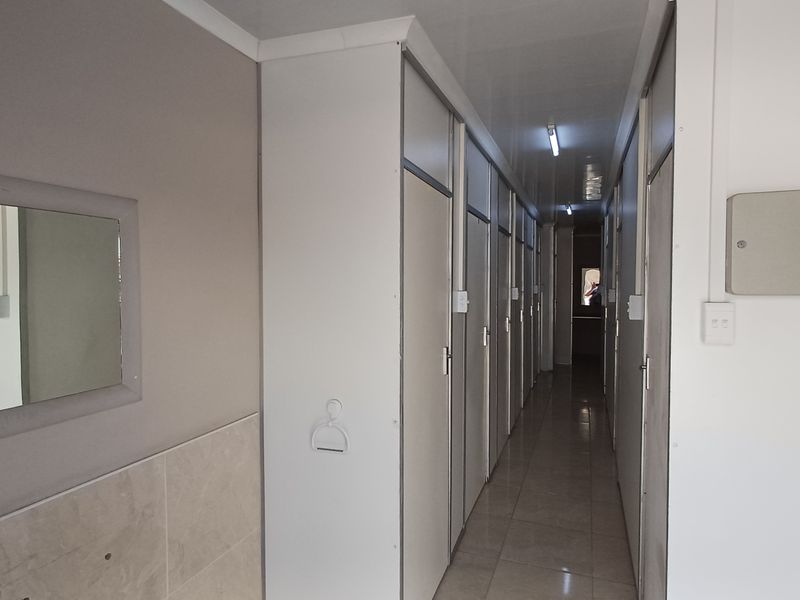 A clean, well-lit office hallway featuring tiled flooring and multiple partitioned office access doors.
