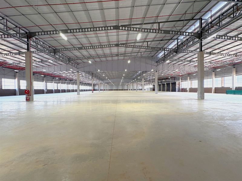 Expansive industrial warehouse space featuring high ceilings, steel truss construction, polished concrete flooring, and integrated fire sprinkler systems.