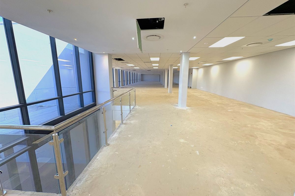 Expansive open-plan industrial office space featuring large windows, structural columns, and a suspended ceiling, currently in a shell condition ready for fit-out.