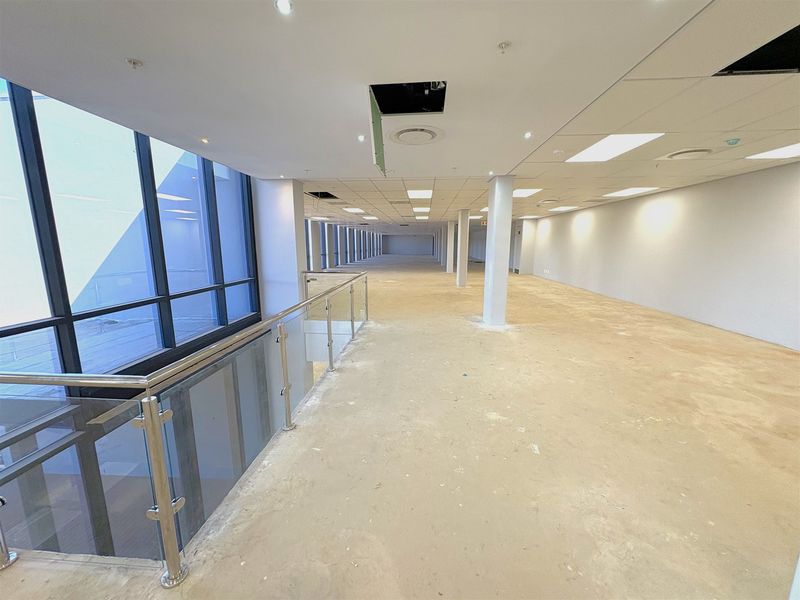 Expansive open-plan industrial office space featuring large windows, structural columns, and a suspended ceiling, currently in a shell condition ready for fit-out.