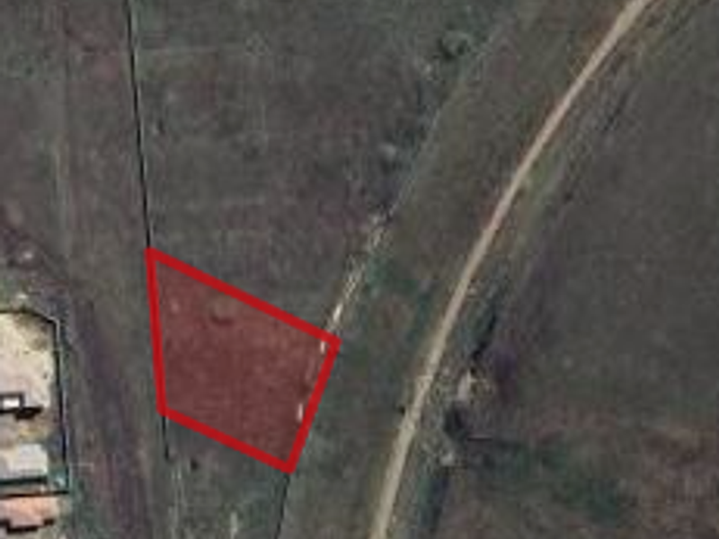 Aerial view of a vacant commercial land plot with perimeter fencing, highlighting the property boundaries and surrounding terrain.