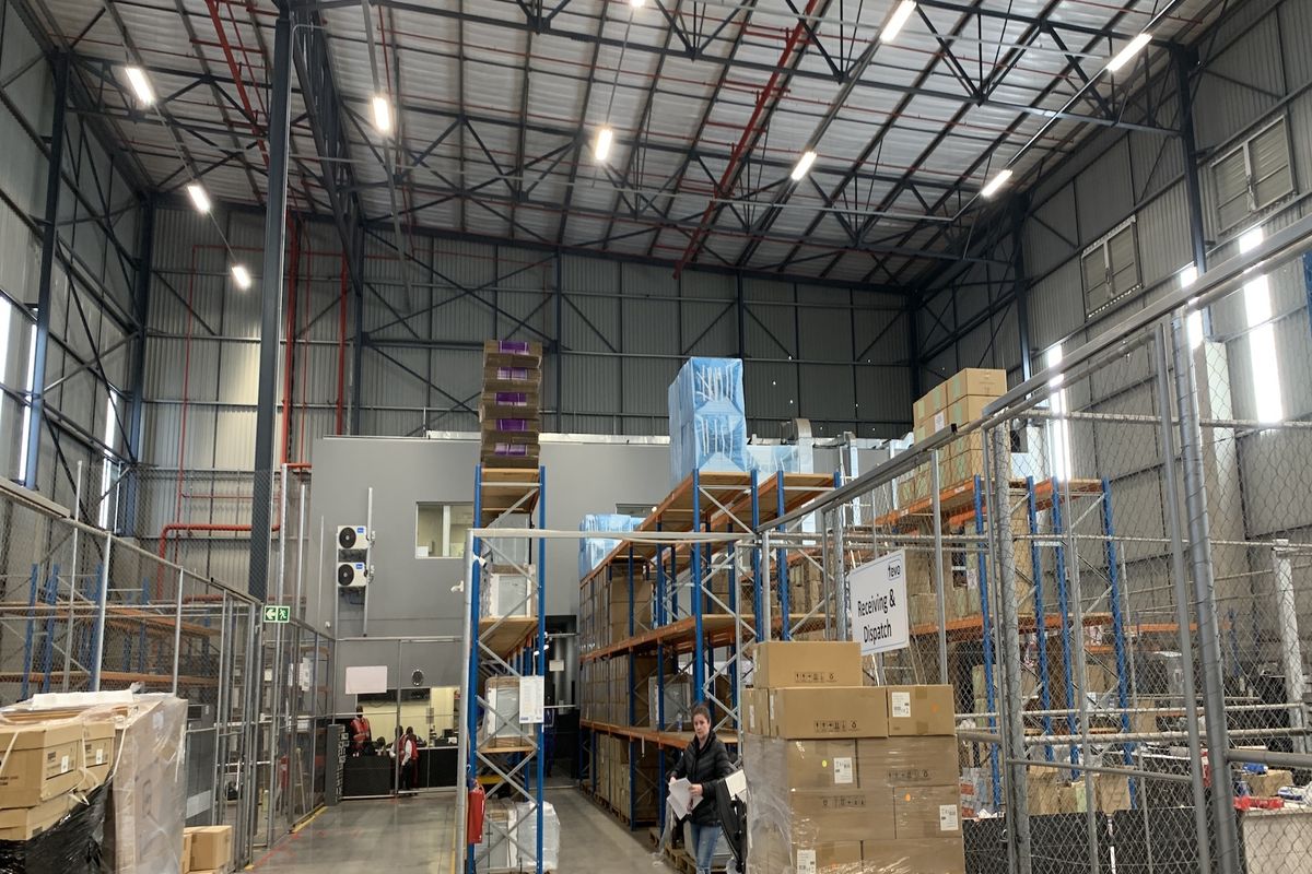 Spacious industrial warehouse facility featuring high-clearance ceilings, exposed steel trusses, integrated fire suppression systems, and secure partitioned storage areas.