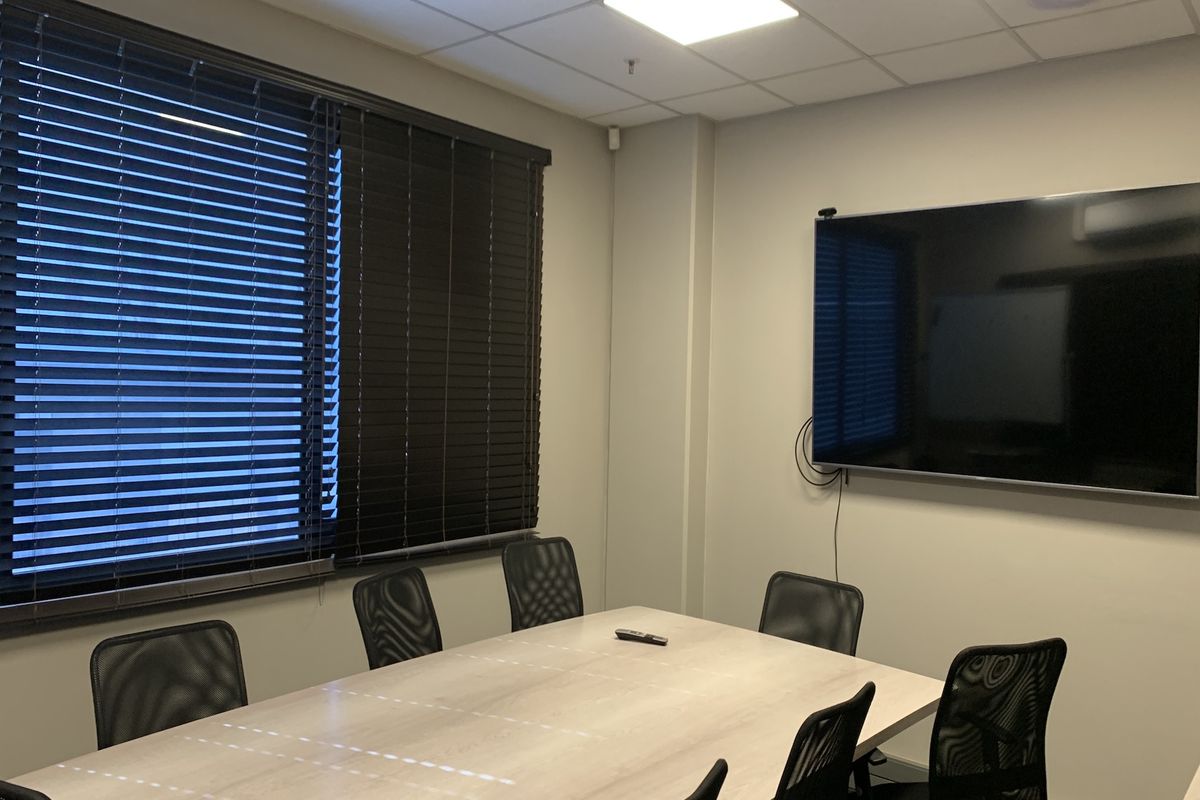 A professional meeting room featuring a suspended acoustic ceiling, recessed lighting, and wall-mounted display screen, suitable for corporate or industrial office use.