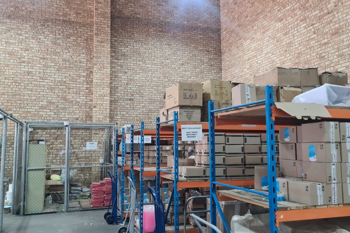 Industrial warehouse space featuring high exposed brick walls, concrete flooring, and heavy-duty steel shelving units for storage.