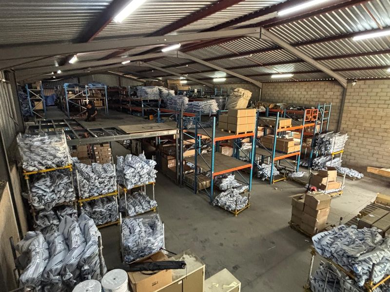 Spacious industrial warehouse featuring a steel portal frame, mezzanine level, and extensive integrated racking systems suitable for storage or distribution operations.