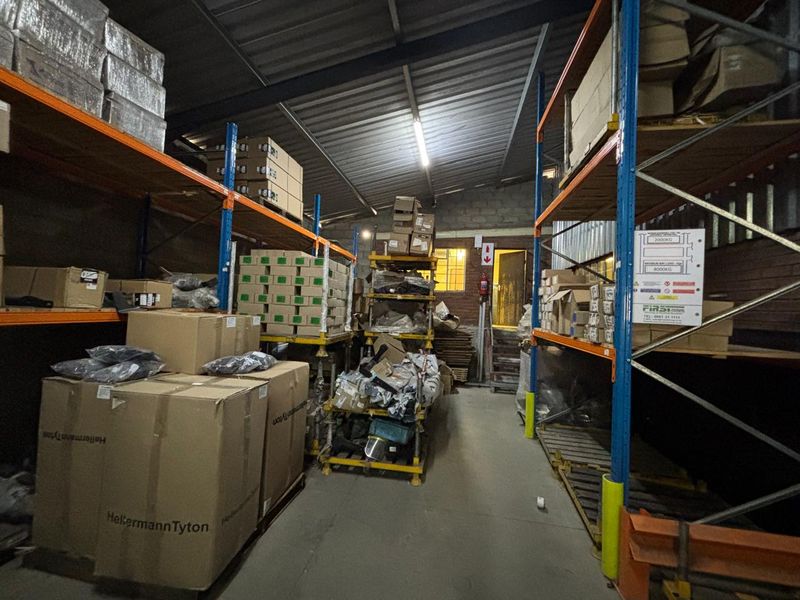 Industrial warehouse storage area featuring heavy-duty steel racking systems, exposed roof structure, and durable concrete flooring suitable for logistics or storage operations.