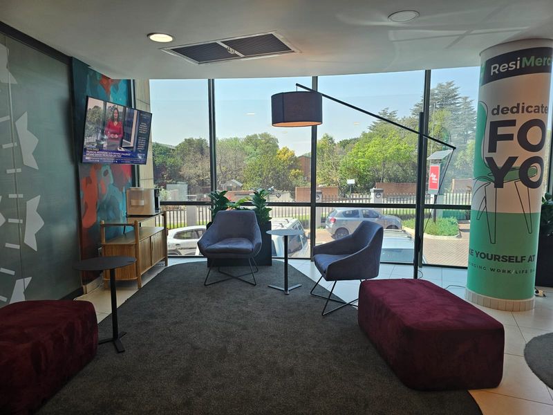 A modern office waiting area featuring floor-to-ceiling windows, recessed lighting, and tiled flooring, providing a bright and professional atmosphere.