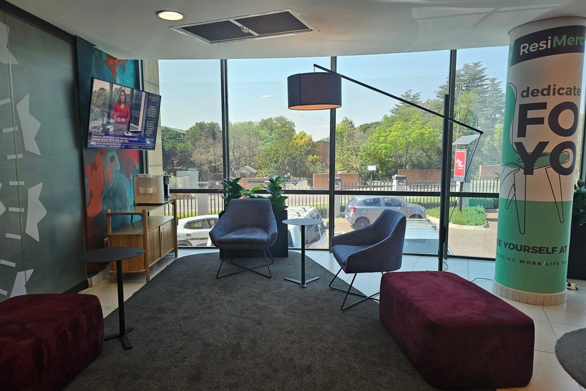A modern office waiting area featuring floor-to-ceiling windows, recessed lighting, and tiled flooring, providing a bright and professional atmosphere.