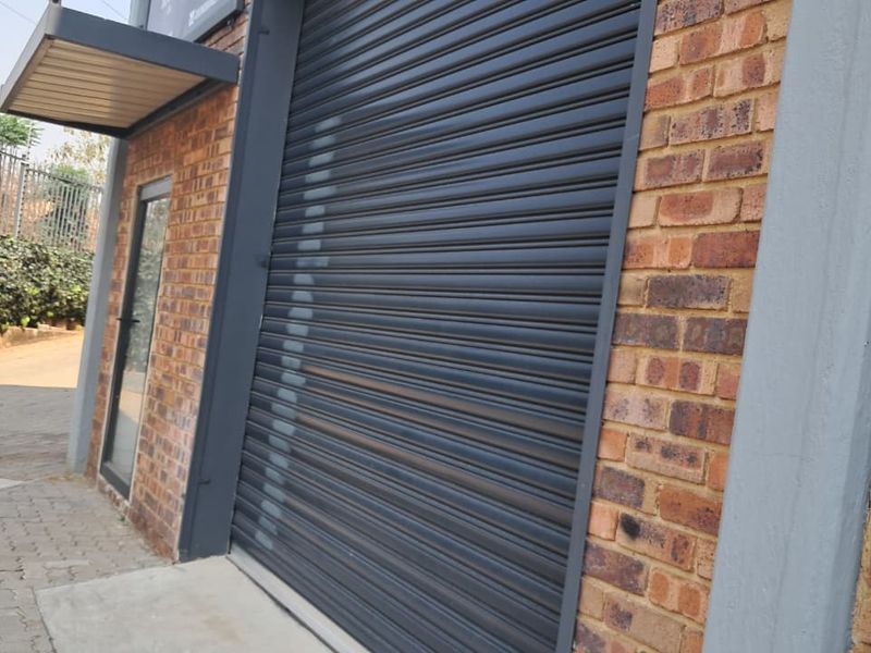Industrial property exterior featuring a secure roller shutter door, brick facade, and paved driveway access.