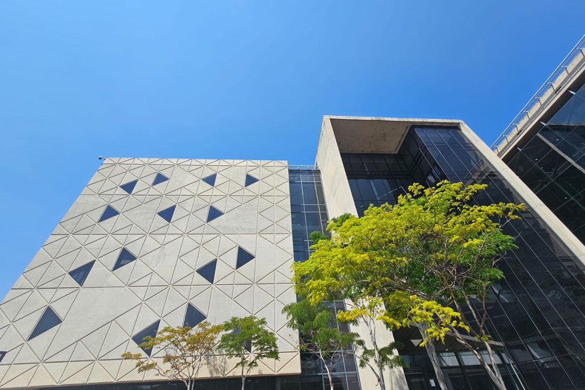 Modern office building exterior featuring a geometric concrete facade and extensive glass curtain walling.