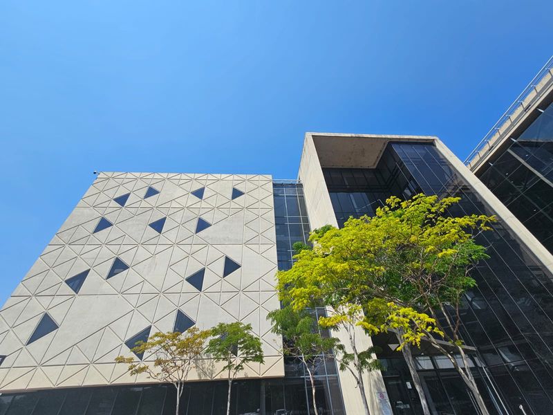Modern office building exterior featuring a geometric concrete facade and extensive glass curtain walling.