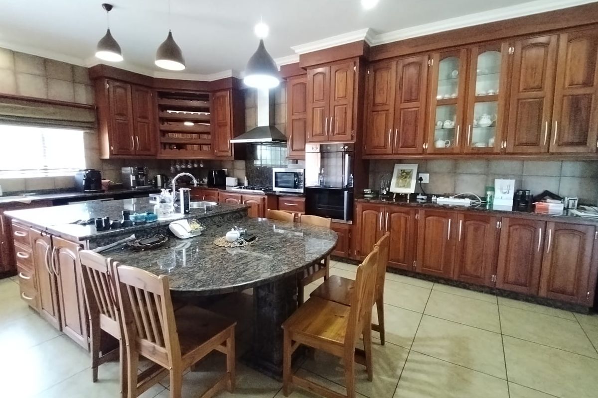 Spacious kitchen featuring extensive wooden cabinetry, granite countertops, a large central island with integrated seating, and built-in appliances.