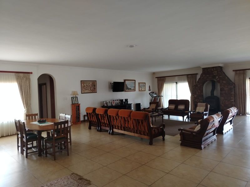 Spacious open-plan living and dining area featuring ceramic floor tiles and a prominent stone fireplace, offering a versatile layout for family living.