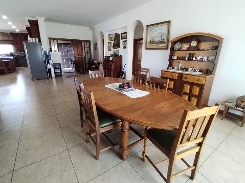 Spacious open-plan dining area featuring tiled flooring and architectural archways, seamlessly connecting to the kitchen and adjacent living spaces.
