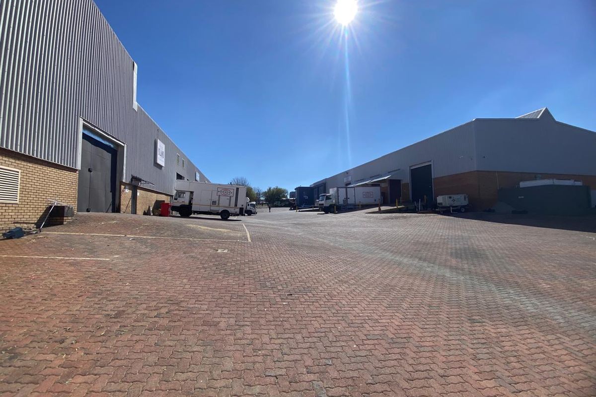 Spacious industrial yard area featuring paved surfaces, large warehouse access doors, and functional loading bays suitable for logistics and commercial operations.