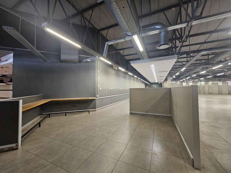 Spacious open-plan retail area featuring industrial-style exposed ceilings, tiled flooring, and a built-in service counter, suitable for various commercial business applications.