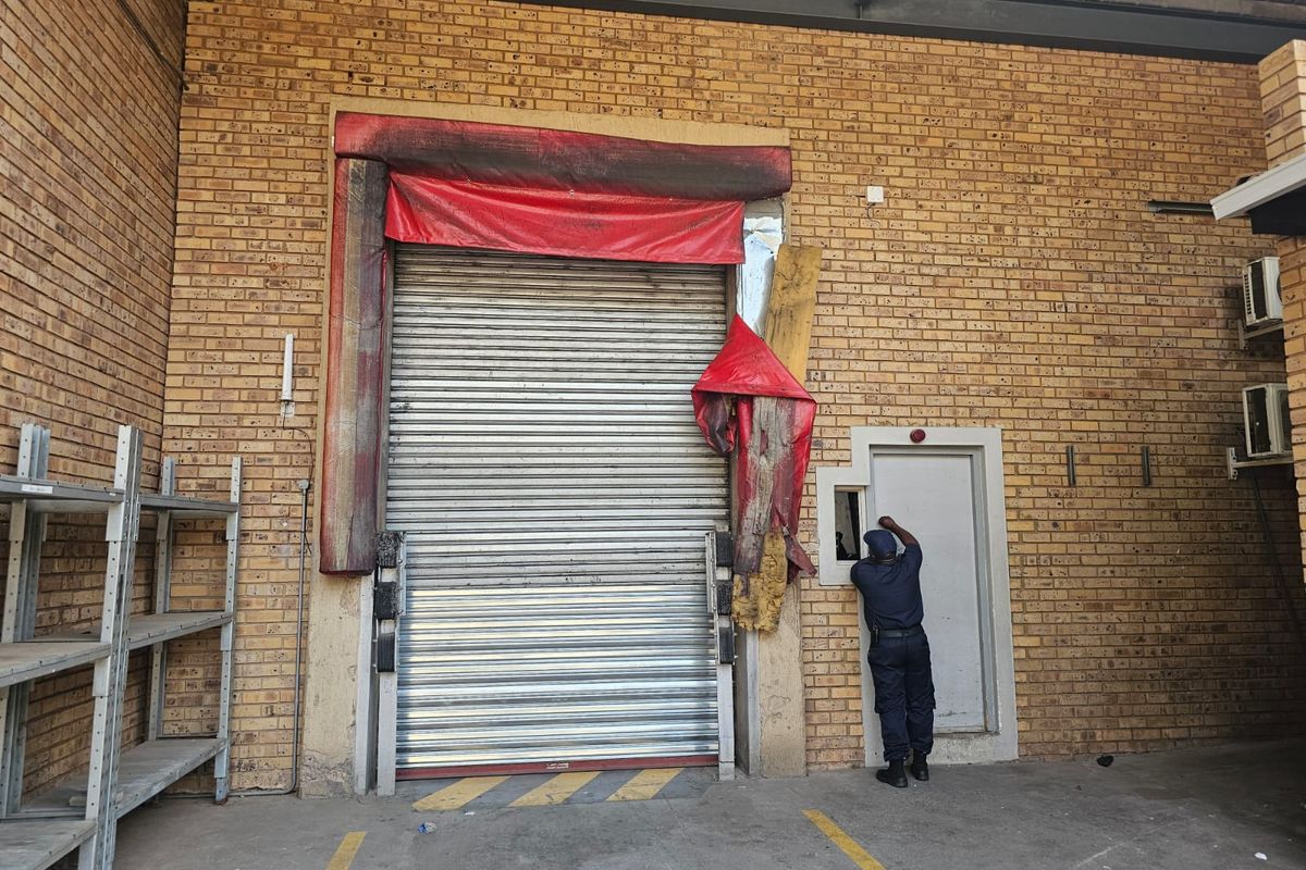 Industrial loading bay featuring a roller shutter door with a damaged dock shelter and brick facade exterior.