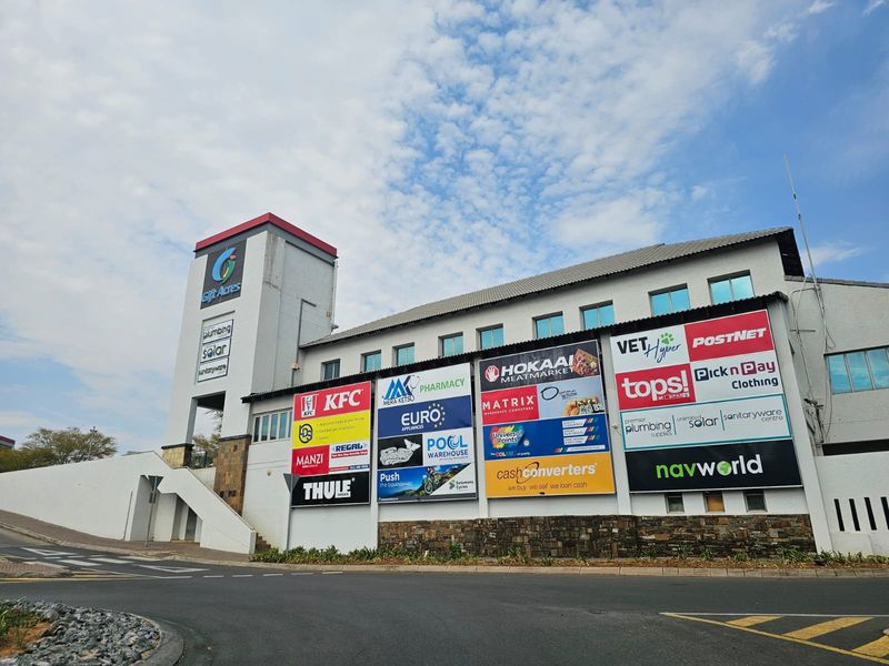 Front elevation of the Gift Acres retail center featuring prominent tenant signage, concrete structure, and stone-clad base.