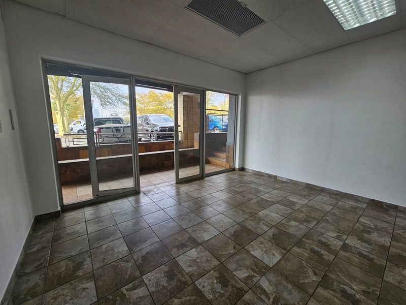 Empty retail entrance area featuring tiled flooring, glass sliding doors, and recessed ceiling lighting, providing a clean and versatile space for business use.