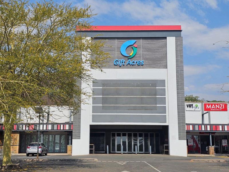 Front elevation of the Gift Acres retail center featuring prominent branding, glass entrance doors, and a paved parking area.